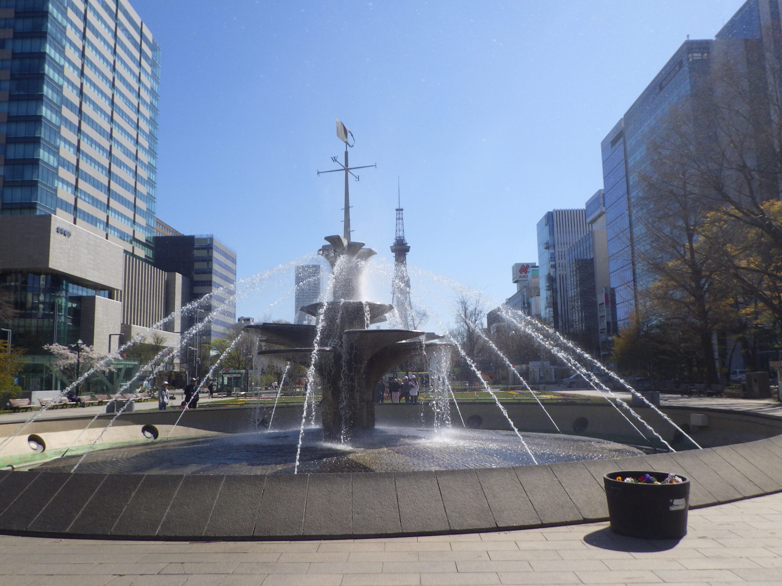 青空の中で西4丁目の噴水が光に反射している画像