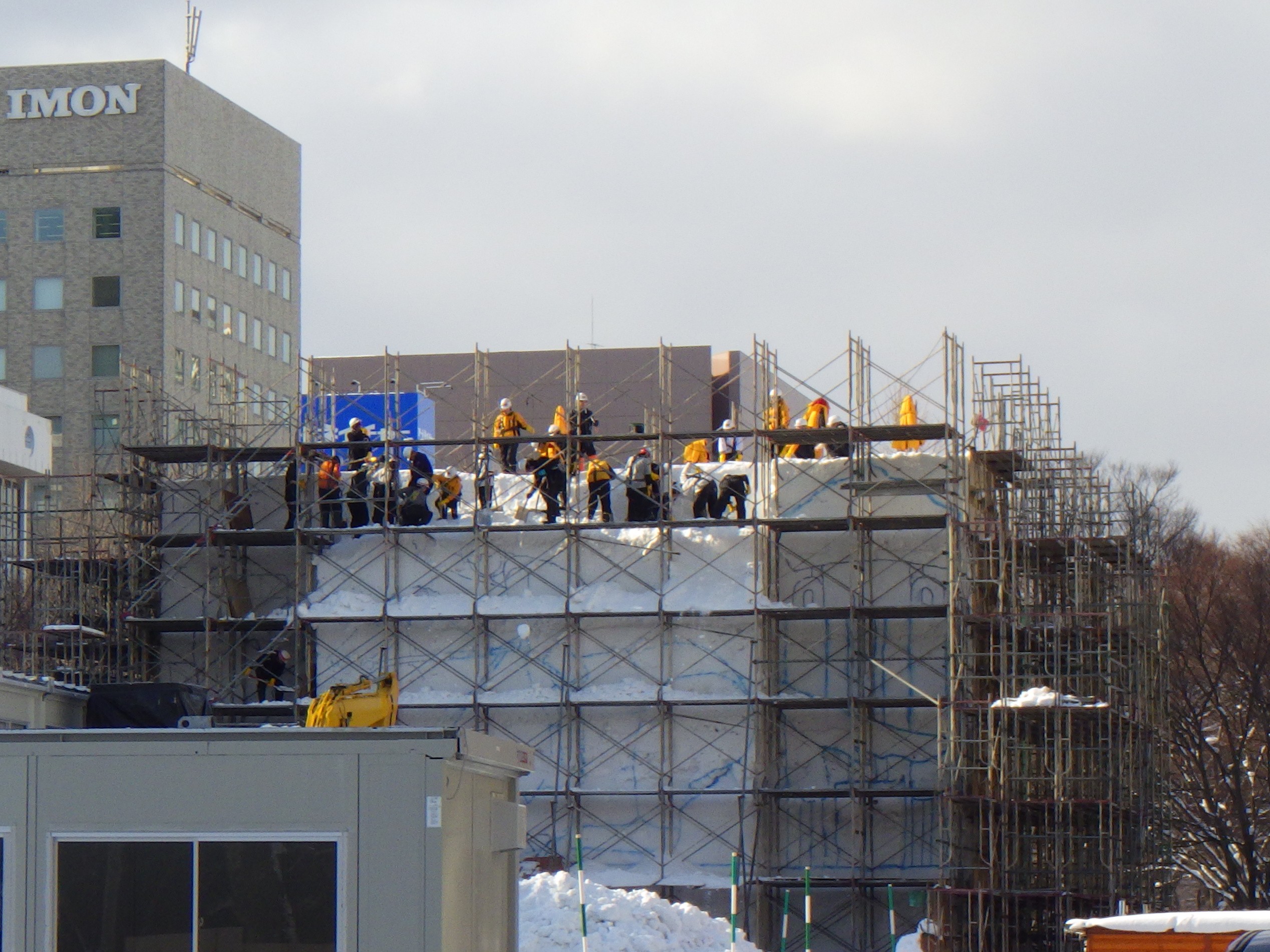 西5丁目道新雪の広場の大雪像制作で雪の上部で雪を削っている画像
