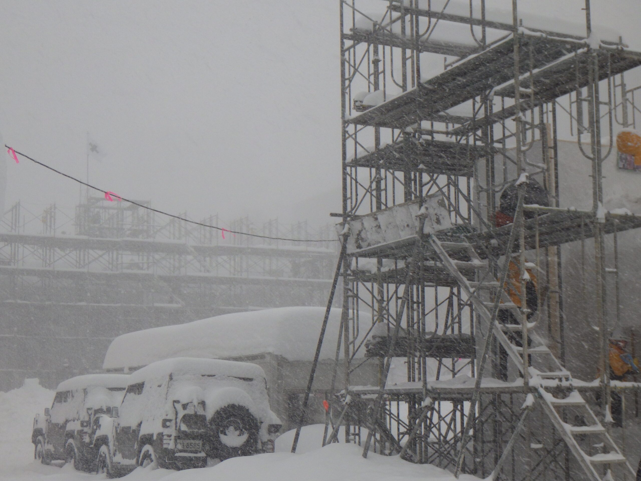 吹雪で視界が真っ白の中の大雪像制作現場の画像
