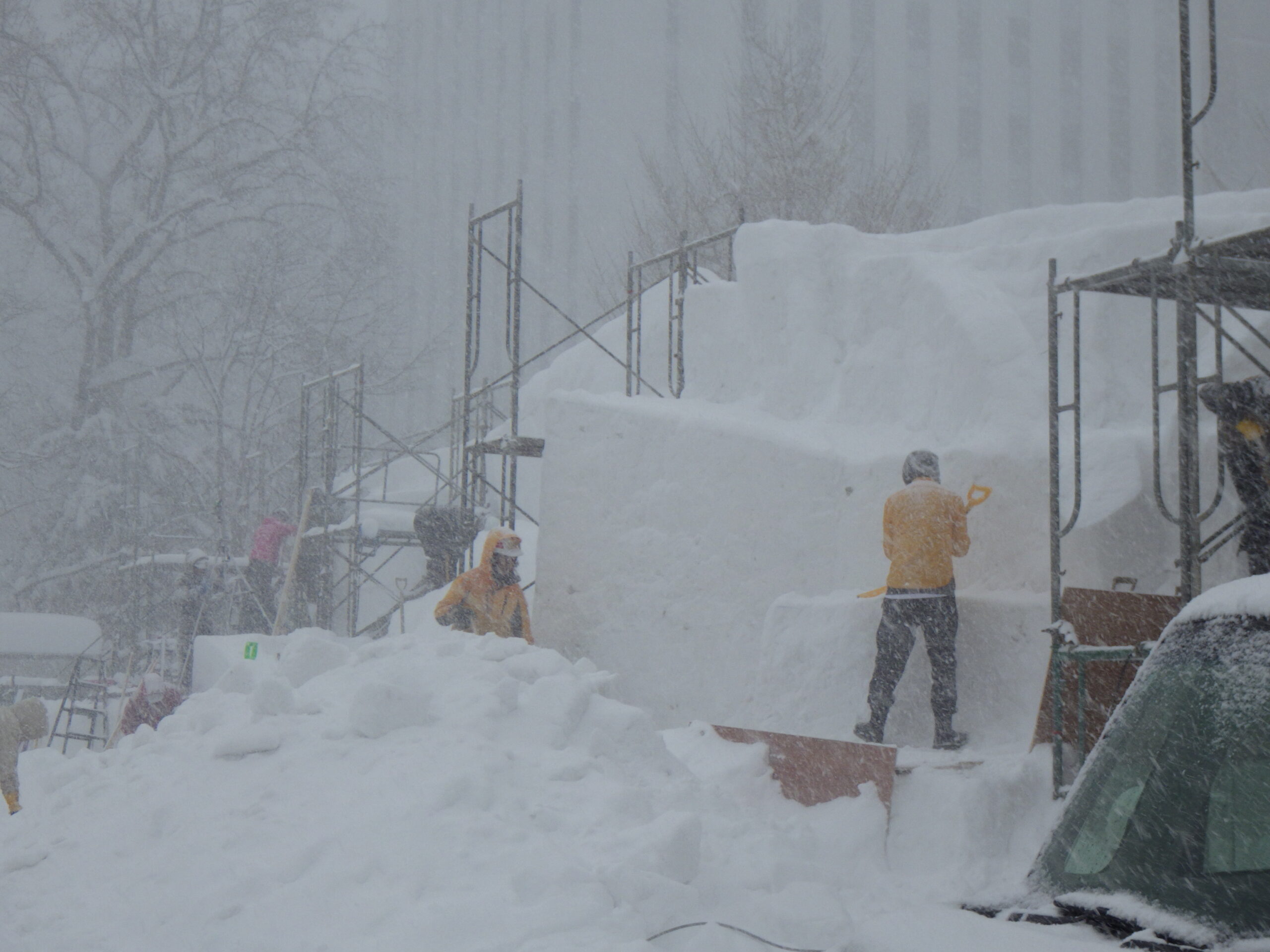 吹雪の中、雪像制作をするスタッフの画像
