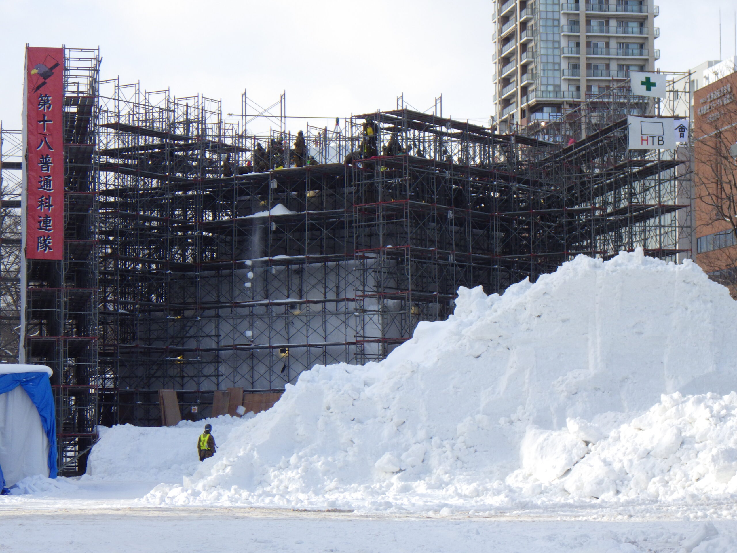 西8丁目で足場の上まで雪を積み上げた陸上自衛隊が雪像制作する様子の画像