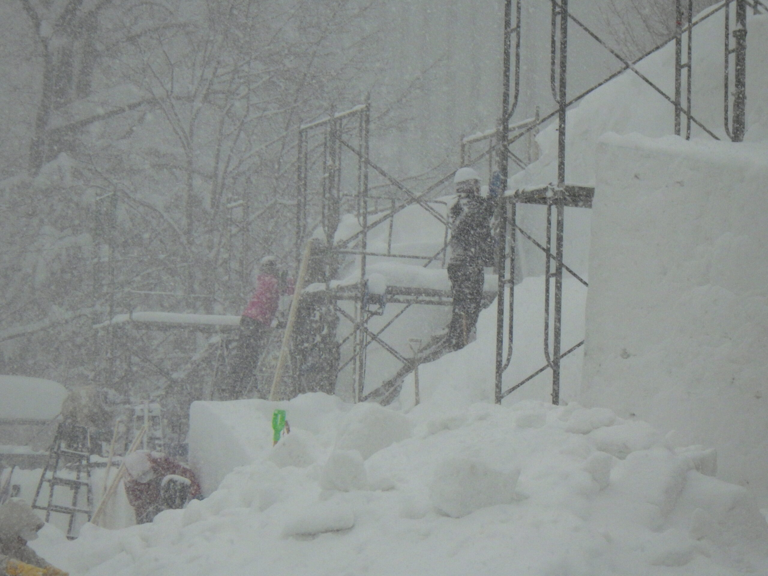 吹雪で視界が悪い中、雪像制作をするスタッフの画像